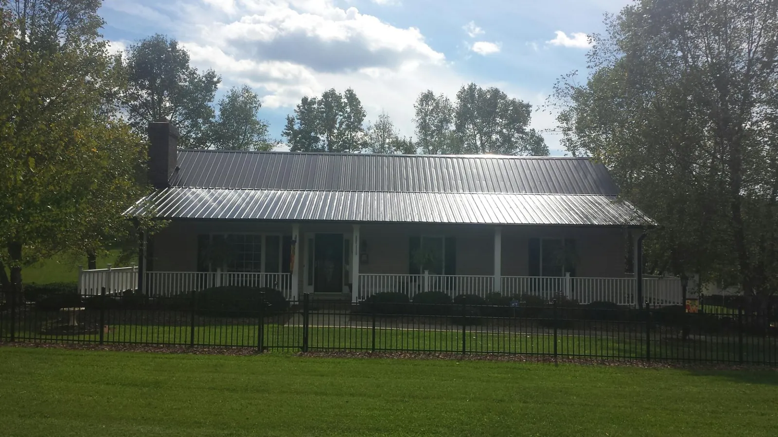Gray metal roof on a brick ranch with a full width front porch — Gutter Guard Installation work by our crew in Mc Henry